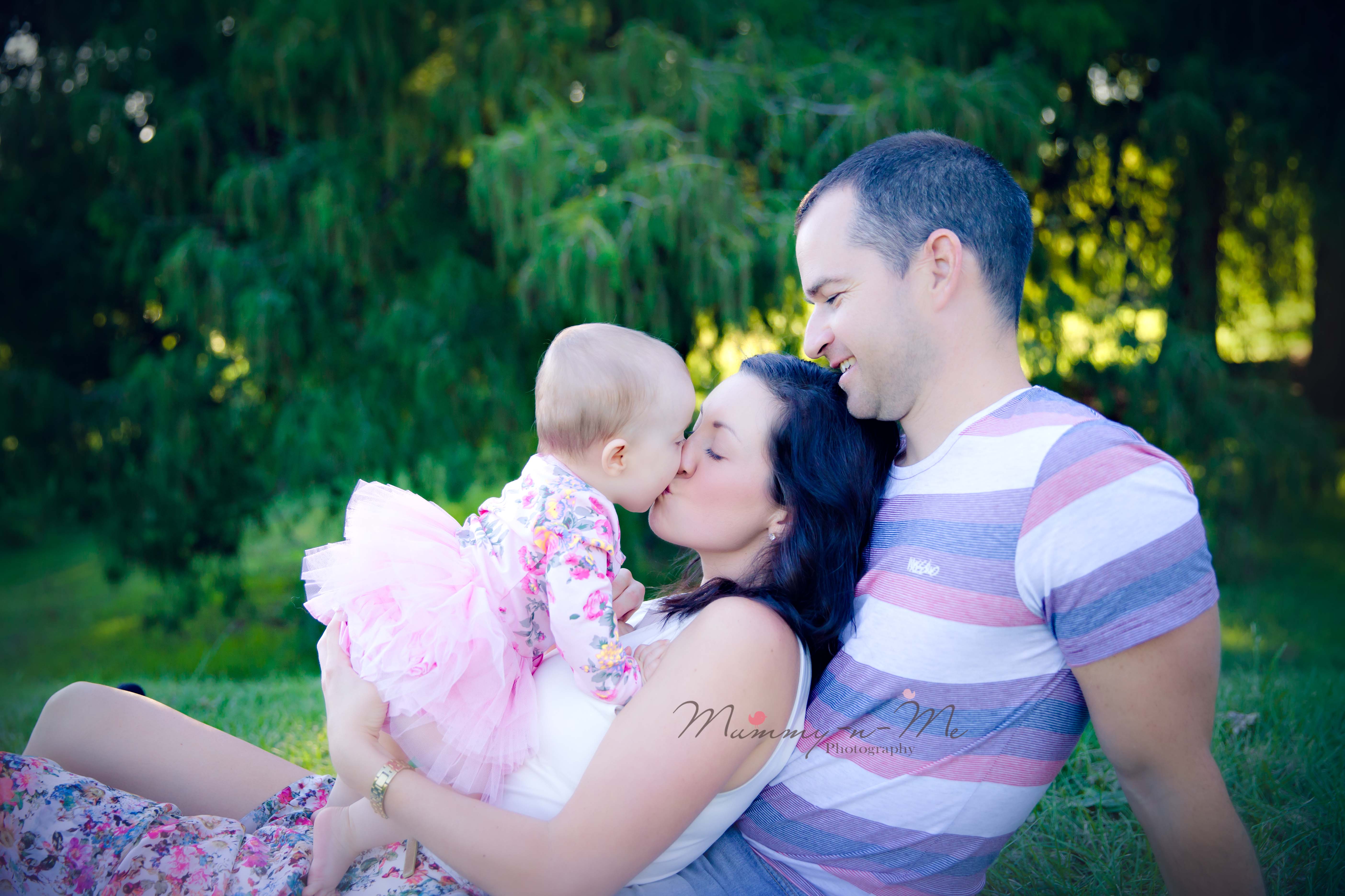 8 month girl with family giving open mouth kisses at the park brisbane family child baby photographer