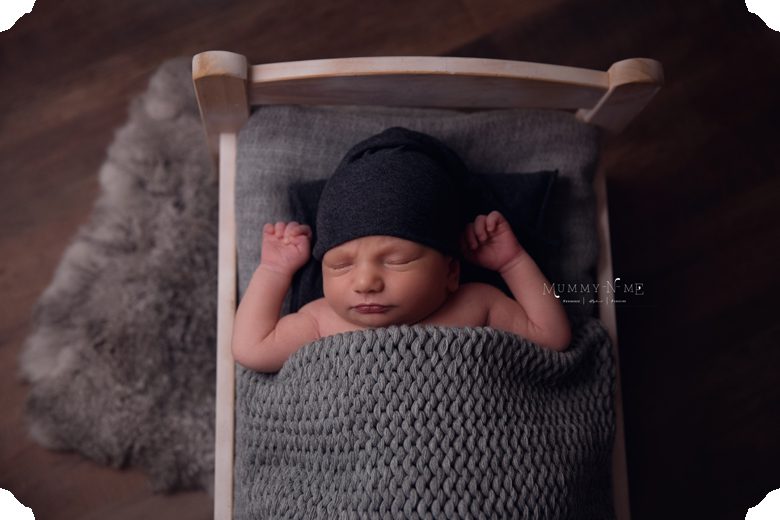 newborn boy on grey bed