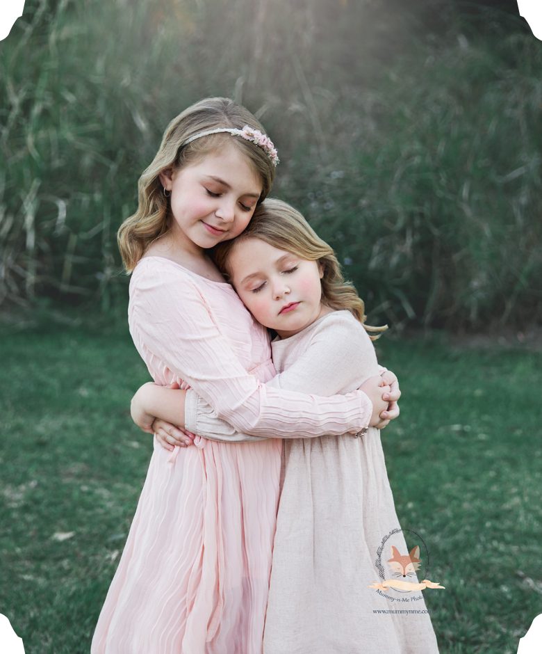 sisters at the park for family photos cuddling 
